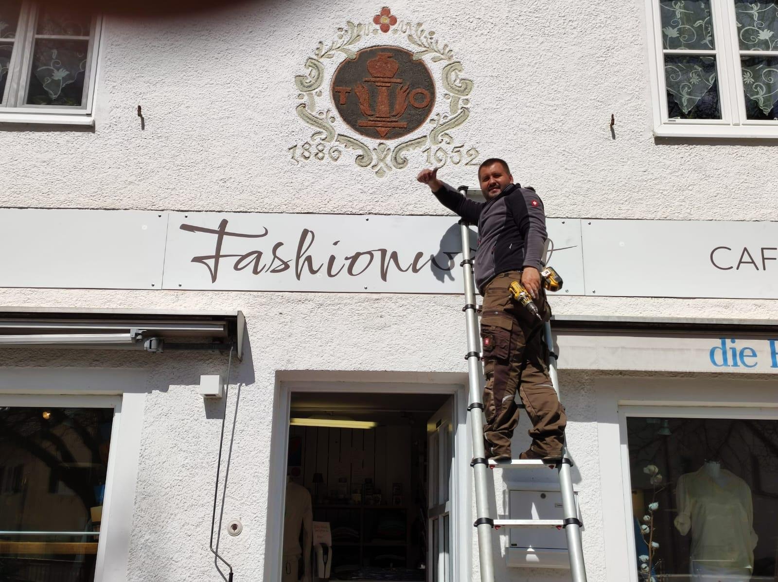 Anbringen eines Werbeschildes vor einem Modeladen